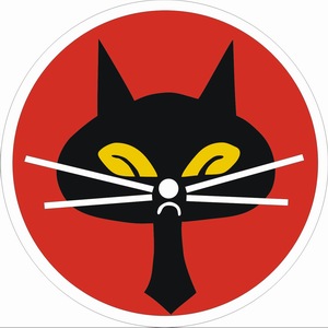 Godło Eskadry Czarny Kot przedstawia głowę czarnego kota z żółtymi oczami na czerwonym tle
