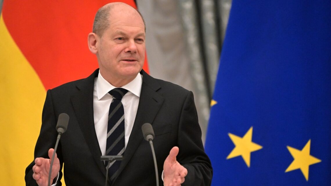 Olaf Scholz na tle flag Niemiec i UE