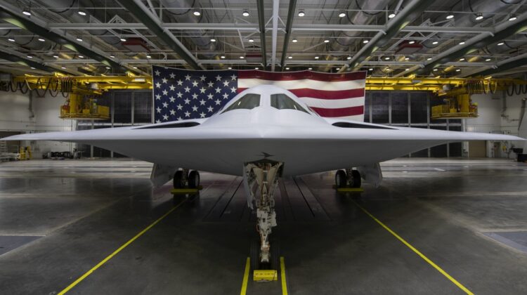 B-21 Raider widziany od przodu na tle flagi USA